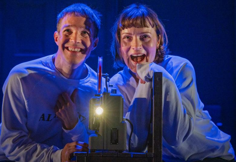 Kuvassa ovat Elena Leeve ja Olavi Uusivirta käyttämässä filmikameraa ja katsomassa kaitafilmejä.  Kuva on sinisen sävyinen.