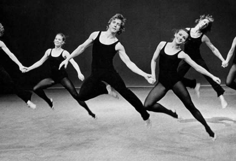Kuvassa on kuusi tanssijaa ilmahypyssä, jossa he ovat jalat vinosti ylhäällä ja kaksittain käsi kädessä. Kuva on musta-valkoinen.