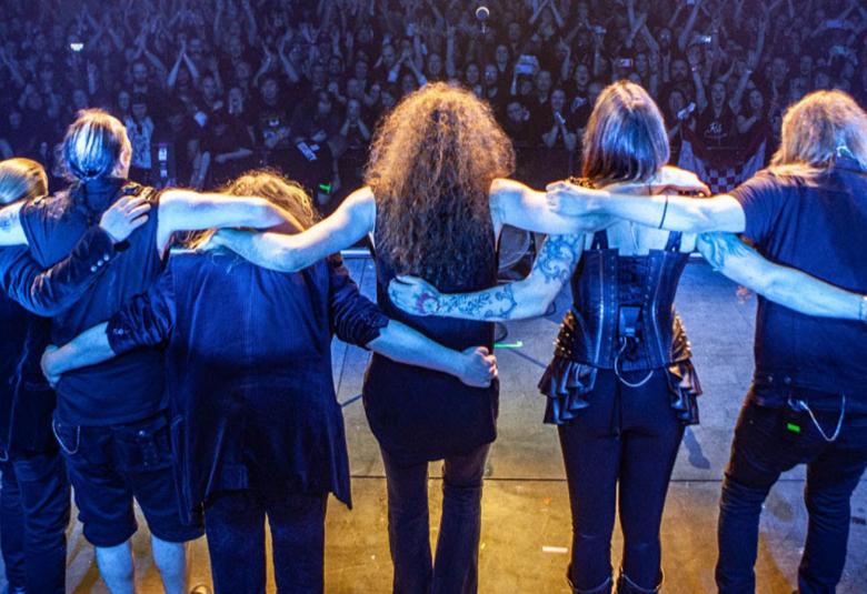 Kuvassa ovat Nightwishin jäsenet seisomassa yleisön edessä Wembleyn stadionilla yleisön edessä yhteiskuvassa. Kuvan sävy on sininen.