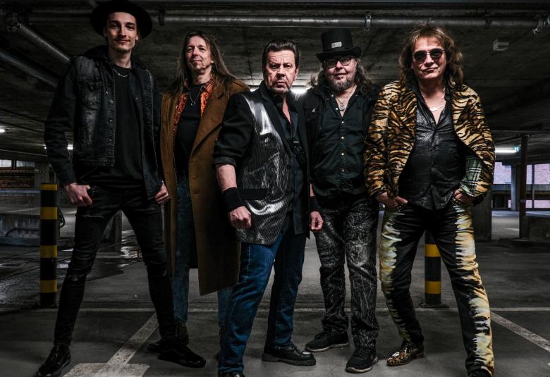 Kuvassa on viisi Popedan jäsentä seisomassa tummissa vaatteissa betonisessa autohallissa.