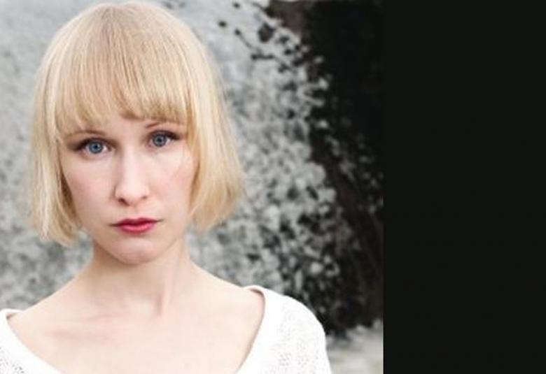 Kuvassa on Ida Rauma vaaleassa polkkatukassa puolivartalokuvassa. Oikea puoli kuvasta on musta ja kuva on musta-valkoinen.