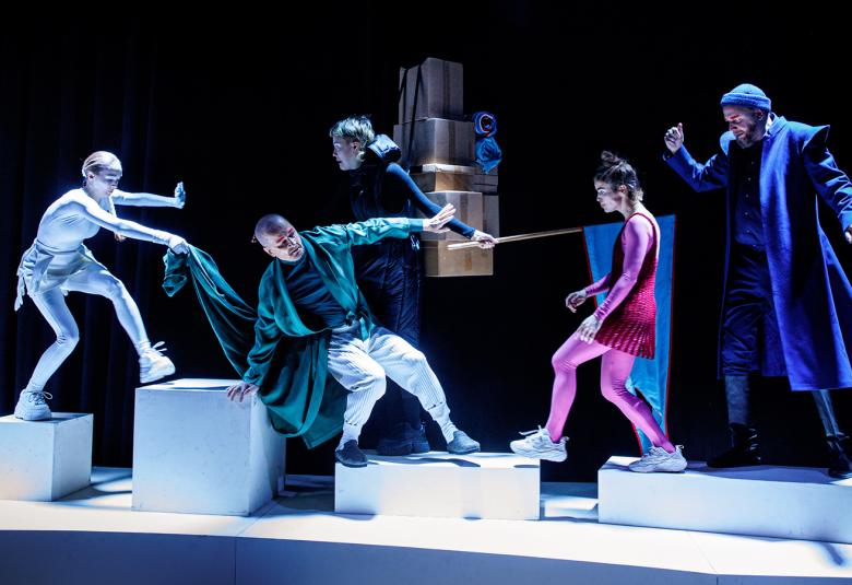 Kuvassa on valkoisten korokkeiden päällä näyttelijöitä erilaisissa jähmettyneissä asennoissa.