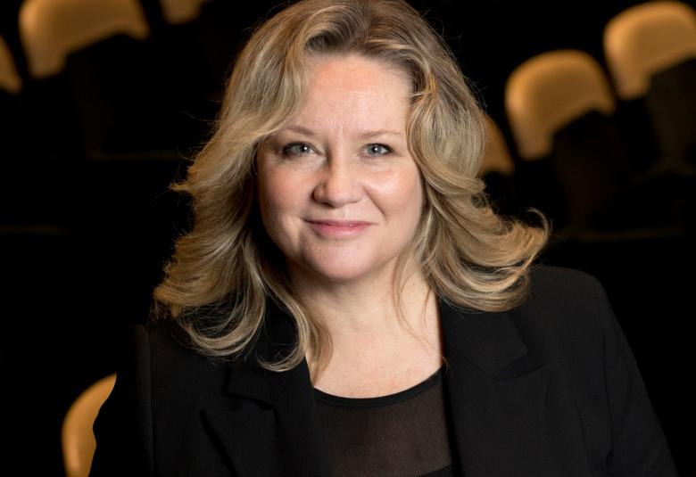 Kuvassa on Maria Sidin kasvokuva.  Hänet on kuvattu yläviistosti istumassa teatterin katsomossa.