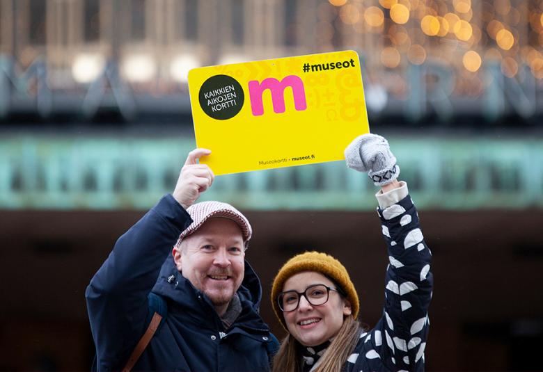uvassa ovat nainen ja mies ja he pitävät kädessään isoa museokortin kuvaa.