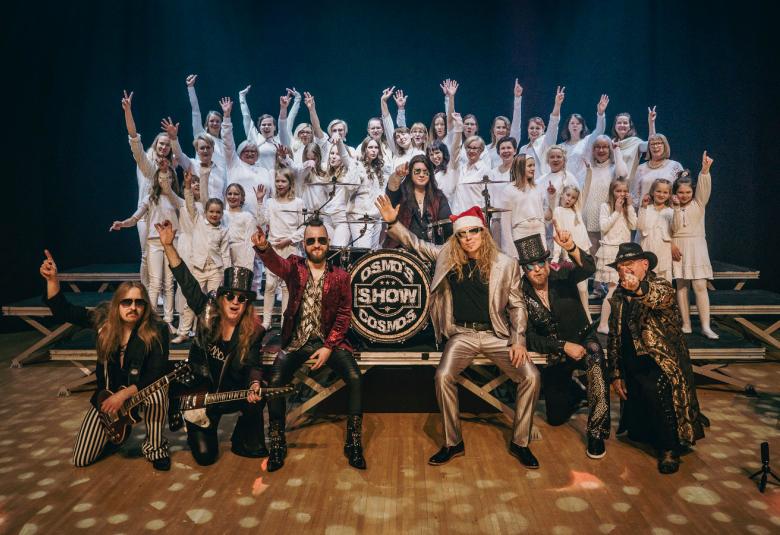 Kuvassa ovat Osmo's Cosmos ruskeissa puvuissa edessä ja takana valkoisissa asuissa kuorot Vuoksen Neiet ja Imatran Immet. 