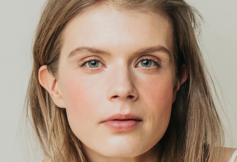 Kuvassa on Alina Tomnikov kasvokuvassa.  Hänellä on vaaleahkot hiukset polkkatukkana.