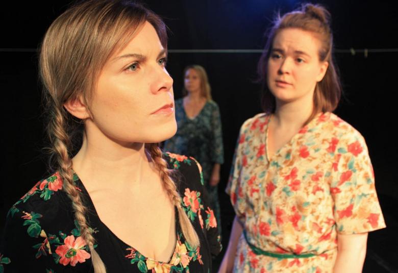 Kuvassa on kaksi naista puolivartalokuvassa.  Vasemman puoleisella naisella on mustapohjainen kukallinen mekko.  Oikean puoleisella on vaalealla pohjalla pastellisävyisiä kukkia.