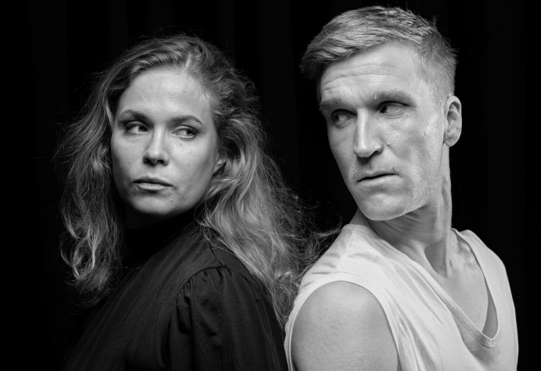 Kuvassa ovat Pihla Viitala ja Juuso Timonen selät puoliksi vastakkain. Kuva on musta-valkoinen ja se puolivartalokuva.