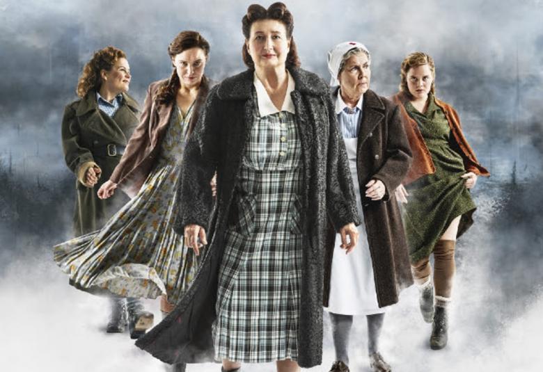 Kuvan keskellä on Heidi Herala vihreä-harmaa ruudillisessä mekossa ja tumman harmaassa takissa. Hänen molemmilla puolillaan on kaksi naista molemmin puolin ja he ovat 1940-luvun vaatteissa.