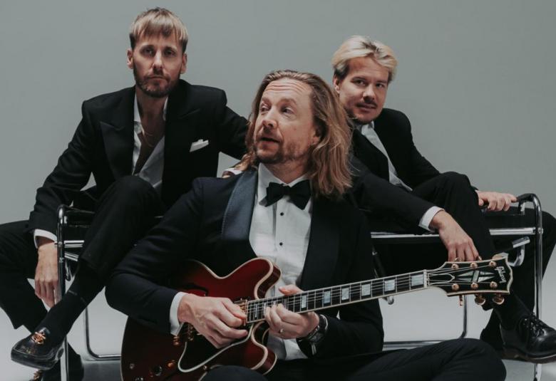 Kuvassa ovat Jare, VilleGalle ja Samu Huber yhteiskuvassa. He istuvat ryhmänä lattialla. 