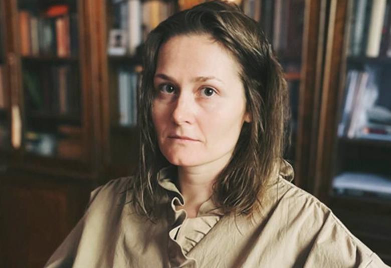 Kuvassa pm Oksana Vasjakinan puolivartalokuva. Hänellä on pitkät tummat hiukset ja vaalean ruskea paitapusero.