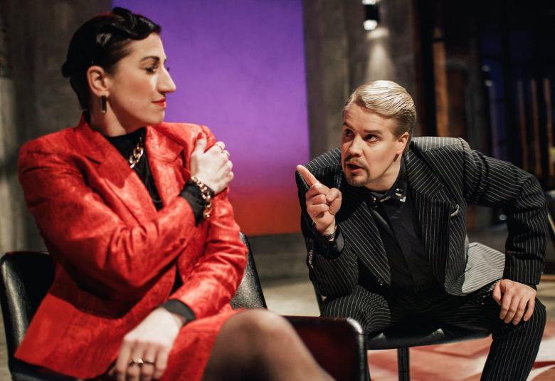 Kuvassa ovat Annina Rubinstein ja Panu Poutanen keskustelemassa.  Molemmat istuvat ja ovat rinnakkain.  Rubinsteinilla on punainen jakkupuku.