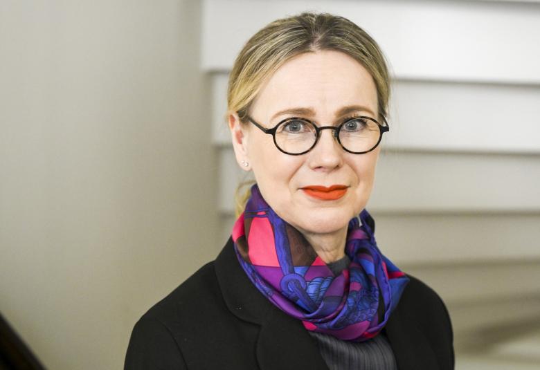 Kuvassa on Susanna Pettersson, josta on puolivartalokuva.  Hänellä on tumma jakku päällään ja tummansininen huivi punaisilla ruutukuvioilla kiedottuna kaulaan.  Taustalla on valkoista portaikkoa takaa päin.