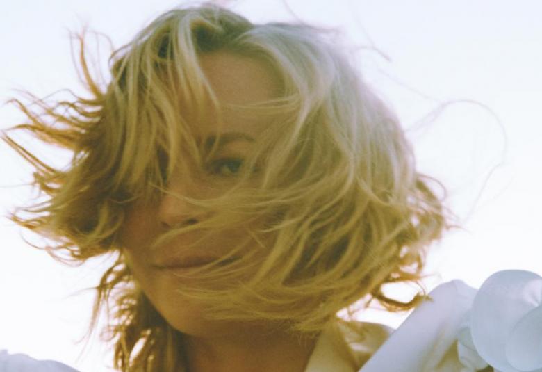 Kuvassa on Paula Vesala kasvokuvassa, jossa vaaleat hiukset hulmuavat tuulessa kasvojen yli.