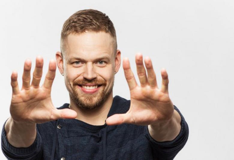 Kuvassa on Signmark puolivartalokuvassa ja hän on kädet ojennettuna eteenpäin. 