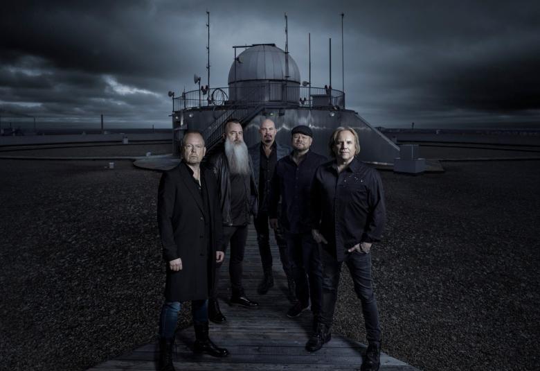 Kuvassa ovat Yö-yhtyeen viisi jäsentä seisomassa tumman sävyisessä kuvassa taustallaan tähtien tarkkailun rakennus, jossa on pyöreä kupoli ja antenneja.