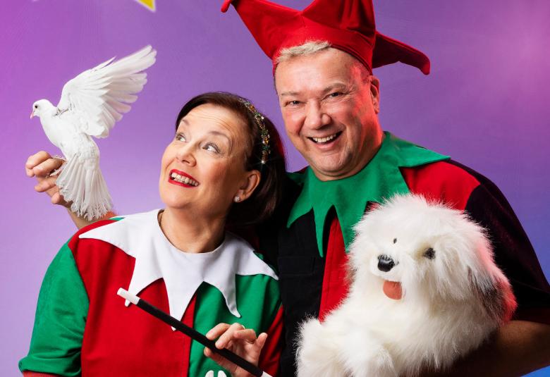 Kuvassa ovat Kirsti vasemmalla valkoisessa harlekiinikauluksella ja Simo Aalto oikealla, jolla on vihreä kaulus.  Hänellä on valkoinen kyyhky oikeassa kädessään Kirstin olkapään takana ja edessään vasemmassa kädessään valkoinen pärröinen koira.