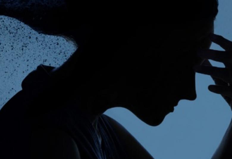 Kuvassa on sinisellä pohjalla musta naisen ylävartalon figuuri ja hän nojaa otsaansa.