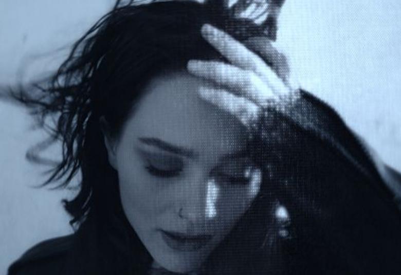 Kuvassa on Sannin kasvot alaspäin jja hiukset liehuvat tuulessa.  Sanni pitää vasemmalla kädellään hiuksista kiinni.  Kuva on musta-valkoinen.