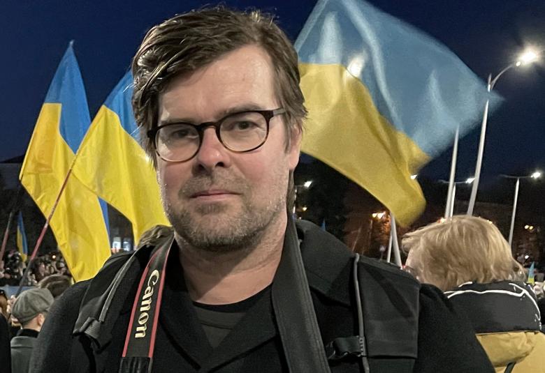 Kuvassa on Antti Hämälinen kameran kanssa ja taustalla liehuvat sini-keltaiset ukrainan liput.