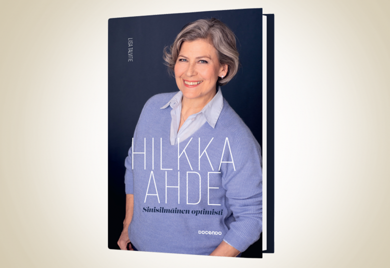 Kuvassa on keskellä kirjan kansi ja siinä on Hilkka Ahde puolivartalokuvassa vaalean sinisessä puserossa.