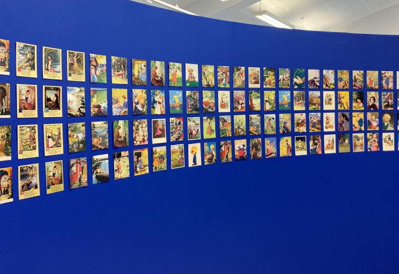 Kuvassa on sinisellä seinäll riveittäin runsaasti postikortteja.