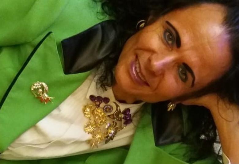 Kuvassa on Harri Henttinen kylkiasennossa vihreässä takissa ja hänellä on korut kaulassaan ja kalvosimissa.