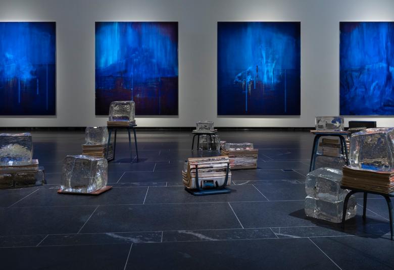 Kuvassa on rivissä neljä sinistä suorakaiteen muotoista taulua seinällä.