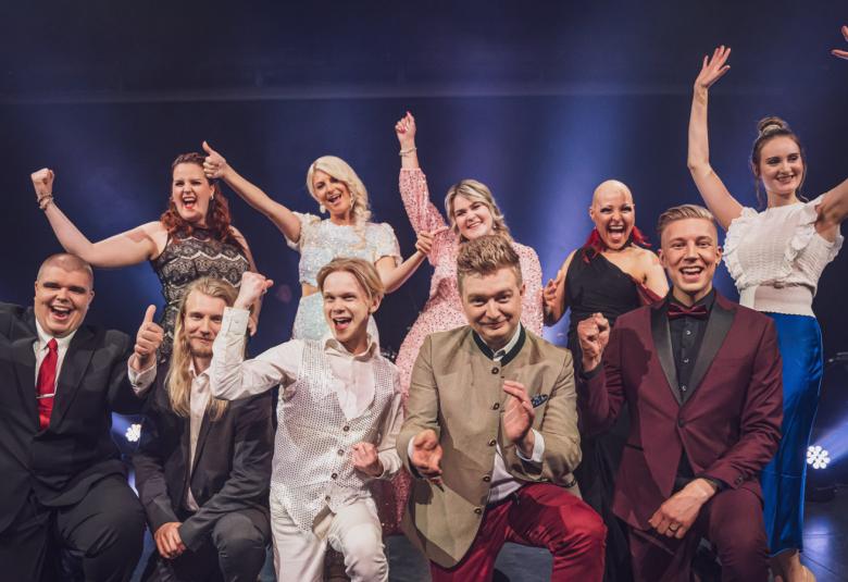 Kuvassa ovat kaikki finalistit ryhmäkuvassa ja he vilkuttavat ja ilmehtivät.