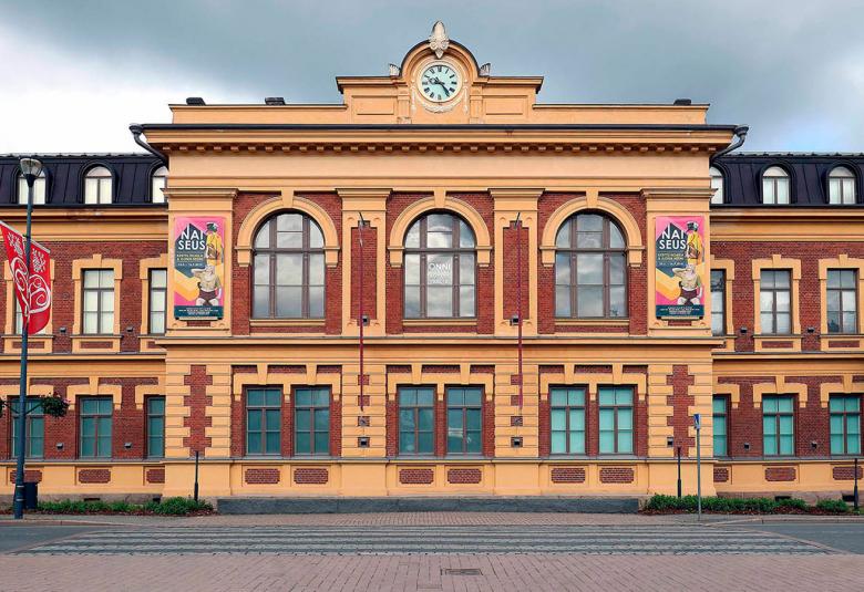 Kuvassa on Joensuun taidemuseon rakennus ja se on klassinen vanha rakennus, joka on väriltään tiilenpunainen keltaisine reunaamaalauksineen.