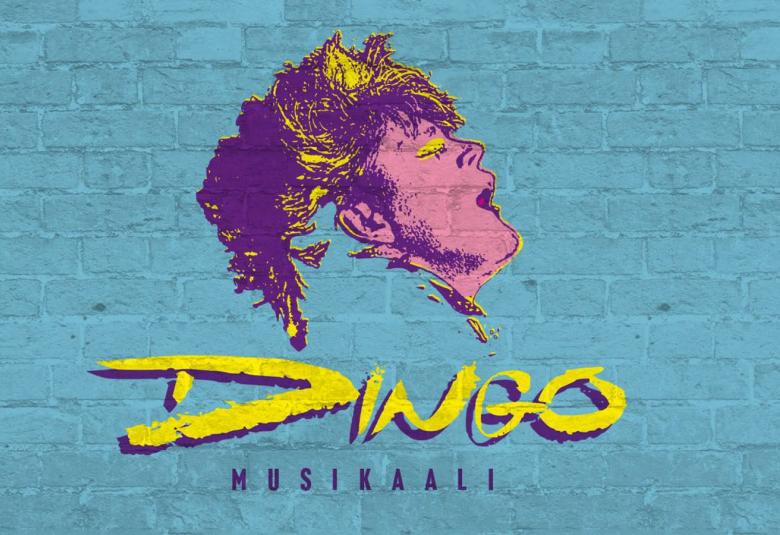 Kuvassa on Dingo-musikaalin juliste ja siinä on harmaata tiiliseinää ja piirretty Neumannin violetin keltainen profiili.  Alla on on teksti Dingo ja musikaali.