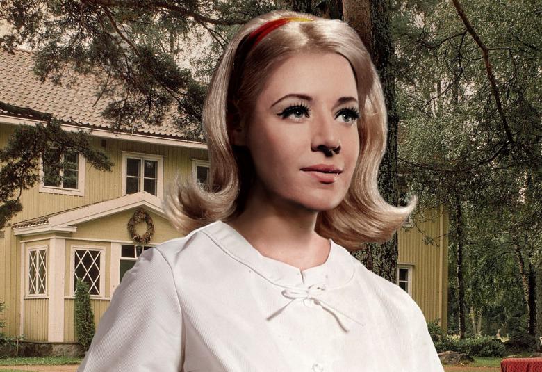 Kuvassa on nuoren naisen kasvot ja hänellä on puolipitkät hiukset.  Taustalla näkyy vaalea talo.  Kuva on piirroskuva.