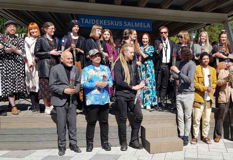 Kuvassa ovat Salmelan kesän taiteilijat useassa rivissä näyttämön edessä.