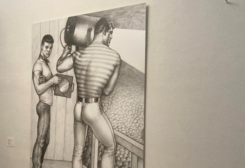 Kuvassa on musta-valkoisena piirroskuvina kaksi miestä, joista vasen seisoo sivuttain katsoen katsojaan. Vasemmalla oleva on selin ja pitää olkapäällään valonheittäjää, joka heijastaa valokeilaa alla olevaan yleisöön.