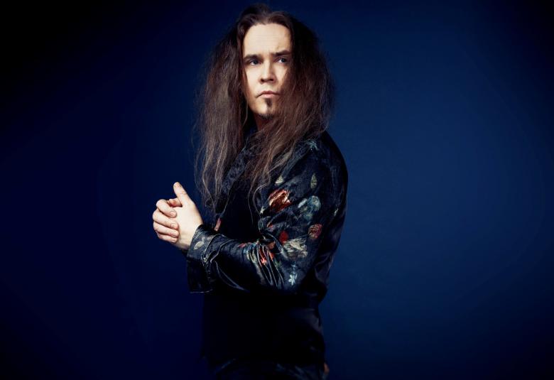 Kuvassa on Jarkko Ahola sivuttain ja katsoo vinosti kameraan.  Kuvan tausta on tumma ja Ahola näkyy osittain.