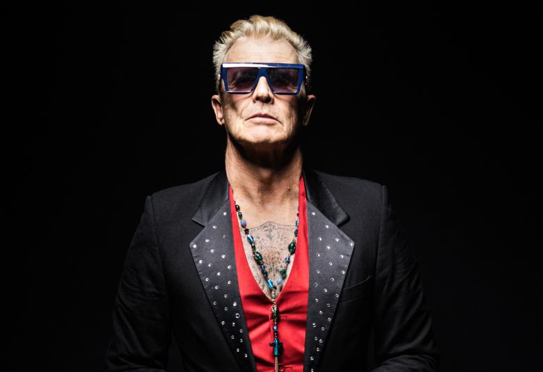 Kuvassa on Eve seisomassa ja hänellä on mustassa puvussa valkoiset kaulukset ja punainen liina kaulusten reunassa alaspäin.