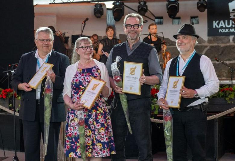 Kuvassa ovat vierekkäin pelimannit Aimo Hentinen, Anita Kaustinen, Juhani Lautamaja ja Patrik WEckman kädessään kunniakirja ja onnitteluruusu.