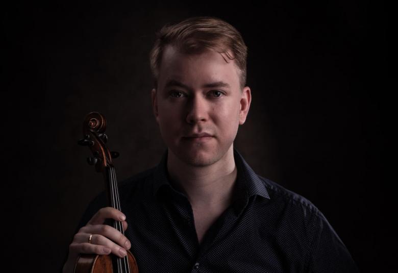 Kuvassa on Elias Lassfolk puolivartalokuvassa ja hänellä on viulu pystysuunnassa oikeassa kädessään.  Kuvan sävy on tumma.