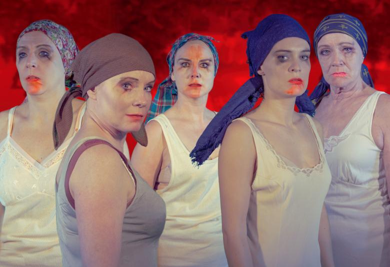 Kuvassa on viisi naista, joilla tiukat huivit päässään ja vaaleat hihattomat paidat päällään.Heillä on punaista huulipunaa.