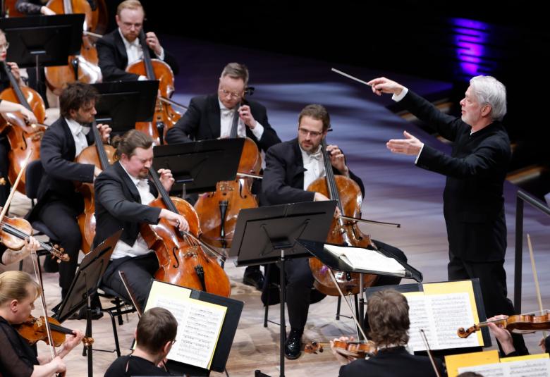 Kuvassa on Jukka-Pekka Saraste johtamassa Helsingin kaupunginorkesteria.  Kuva on otettu yläviistosta ja sivusuunnassa. 