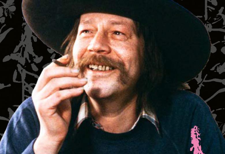 Kuvassa on Irwin Goodman kasvokuvassa ja hän katsoo hymyillen siviulle päin.  Hänellä on musta lierihattu päässään ja pitkähköt hiukset. Hänellä on tupakka oikeassa kädessään.