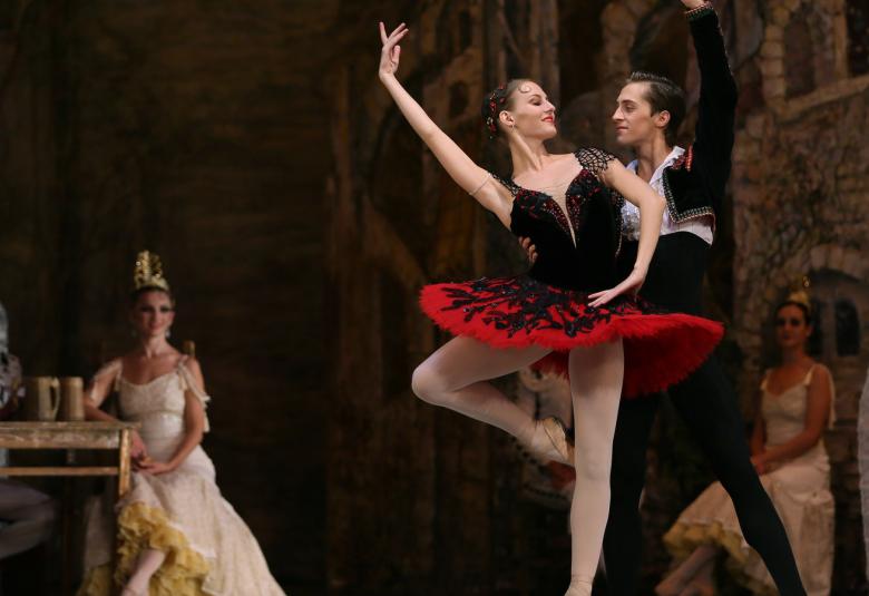 Kuvassa ovat oikealla Daryna Kirik puna-mustassa balettipuvussa ja oikea käsi ojennettuna ja oikea jalka kulmassa sekä toinen jalka ojennettuna.  Vieressä on Arsen Masurenko seisomassa ja pitää kiinni Kirikistä.  Vasemmalla on istumassa kultaisen pöydän ääressä valkoisessa puvussa ballerina.