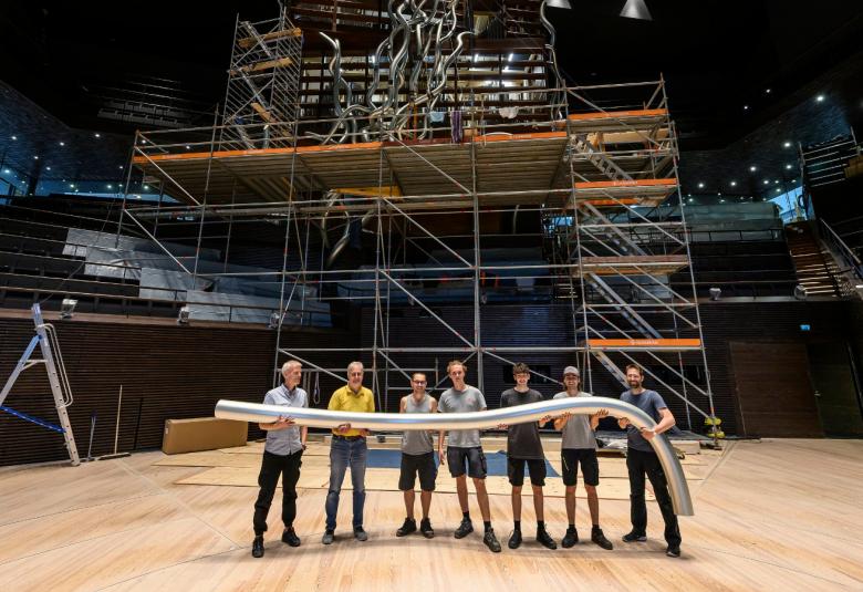 Kuvassa on Musiikkitalon orkesteritaso ja siinä seisoo seitsemän miestä pitelemässä urkypilliä.  Taustalla on rakennustellingit urkujen rakennusta varten.