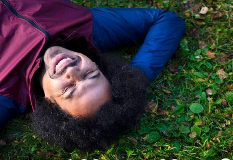 Kuvassa on Sean Ricks makaamassa ruohikolla pää alaspäin kuvan vasemmassa nurkassa. Ruohikko on vihreää ja kuvassa näkuvät Ricksin kasvot ja kädet pään alla sini-lilassa verkkarissa.