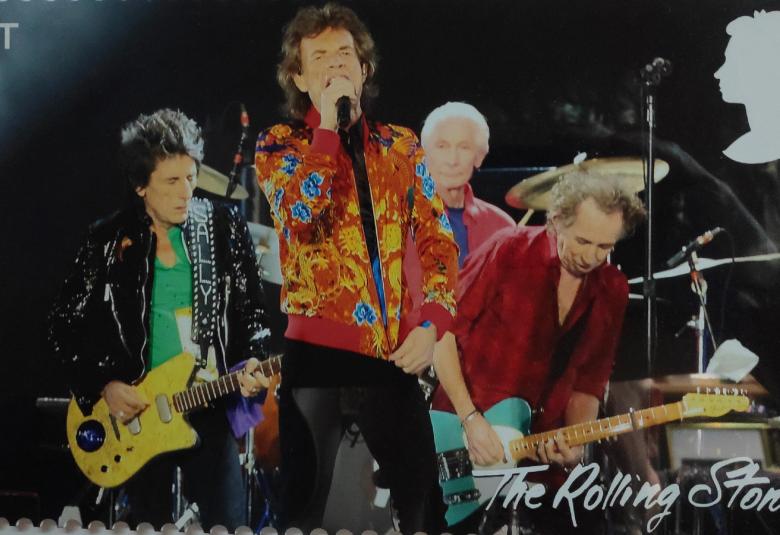 Kuvassa on Rolling Stones -yhtyeen postimerkki. Siinä ovat kitaristit takana ja edessä Keith Richards laulamassa mikin kanssa. Hänellä on punainen takki päällään.  