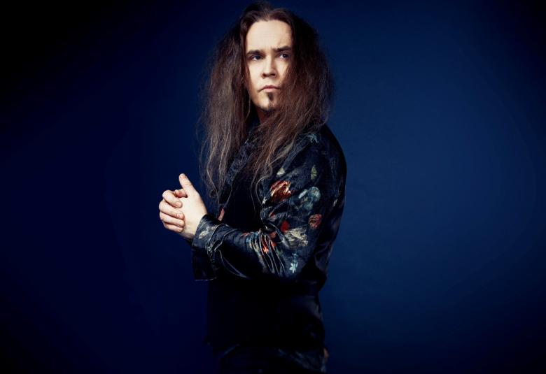 Kuvassa on Jarkko Ahola kääntyneenä sivuttain vasemmalle ja katse käännettynä oikealle. Hänellä on musta nahkatakki ja tausta on tumman sininen. Aholalla on pitkät, ruskeat hiukset.