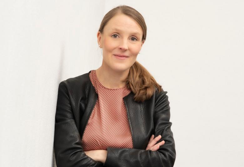 Kuvassa on Kiira Miesmaa ja hänellä on hiukset poninhännällä. Päällään hänellä on ruskea villatakkija roosa t-paita. 