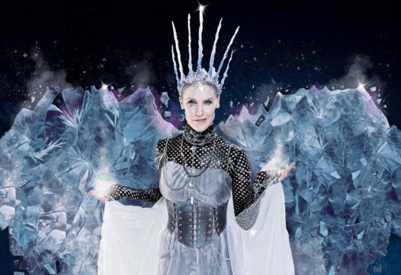 Kuvassa on Vappu Nalbantoglu Lumikuningattarena. Hänellä on harmaan ja valkoisen kirjava puku ja jäämäiset siivet takana. 