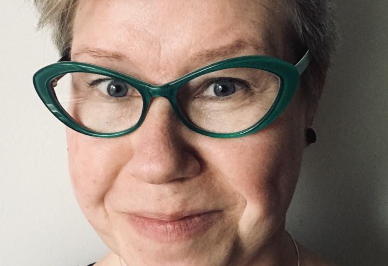 Kuvassa on Sarianne Tursas ja hänestä on kasvokuva. Hänellä on tummasankaiset silmälasit.