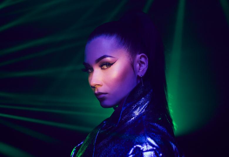 Kuvassa on Bessin kasvot ja hän on vinoittain katse katsojaansa.  Hänellä on tummat hiukset ylös nostettuna.  Hänellä on musta kiiltävä nahkatakki päällään.  Tausta on tumma ja vasemmalta tulee vihreitä valojuovia.